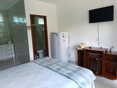 a bedroom with a refrigerator and a sink and a desk at Flats 3 Locação Penedo RJ in Penedo