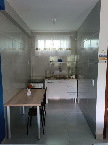 a small kitchen with a wooden table and a sink at Flats 3 Locação Penedo RJ in Penedo
