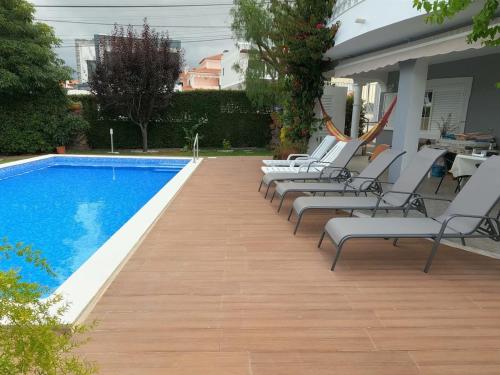 a row of lounge chairs next to a swimming pool at Luxury Apartment 4 Bedrooms Pool in Marisol in Corroios