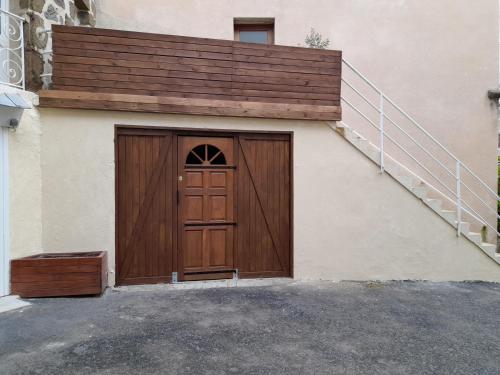 a garage with a wooden door and a set of stairs at Tour médiévale de l'an mille in Loudes