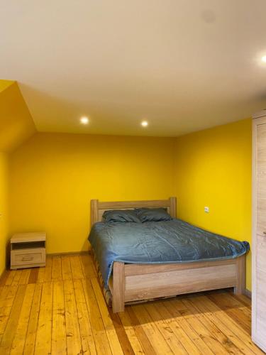 um quarto com uma cama numa parede amarela em Aņutas flat em Saldus