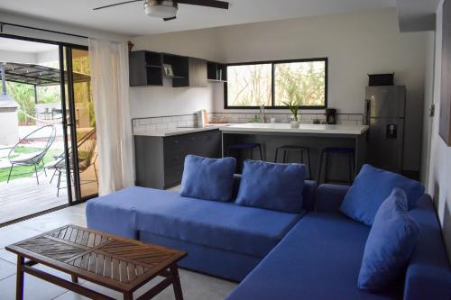 a living room with a blue couch and a kitchen at Blue Window Boutique Villas Hotel in Playa Junquillal