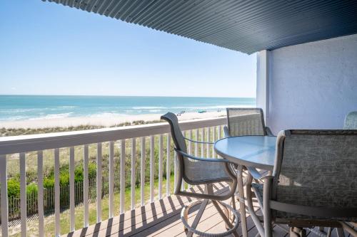 Un balcón con mesa y sillas y el mar. en Oceanfront Condo with pool - Walk to the Tiki Bar, en Carolina Beach