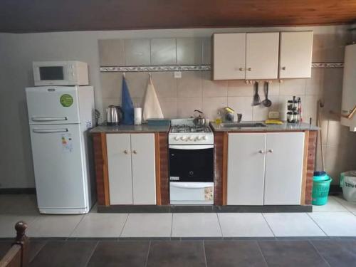 a kitchen with white cabinets and a stove and a refrigerator at Emilia I in Esquel