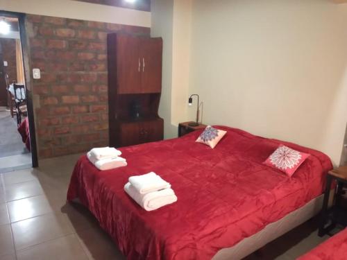 Un dormitorio con una cama roja con toallas. en Emilia I en Esquel
