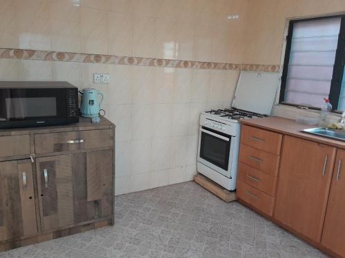 a small kitchen with a stove and a microwave at Jiso Family Apartment in Tamale