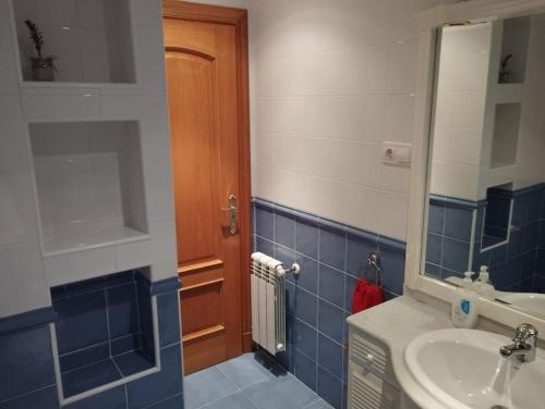 Baño azul con lavabo y espejo en AR Villa Rica Apartment en Santa Comba