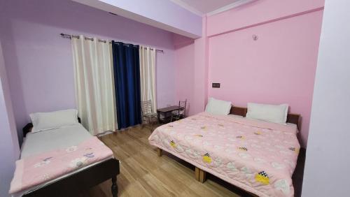 Hotel Aashirwad في Chamoli: سريرين في غرفة بجدران وردية وأرجوانية