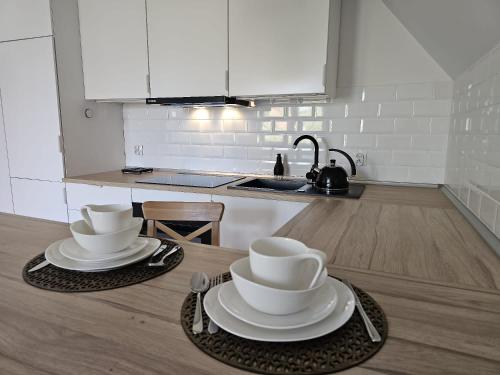 a kitchen with two plates and cups on a table at Apartament w sercu Oliwy in Gdańsk