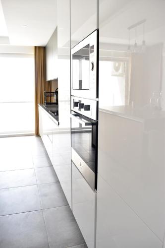 a kitchen with white appliances and a white tile floor at Golden Rays Apartment in Nadur