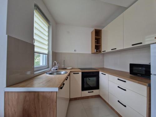 a kitchen with white cabinets and a sink and a window at N&M Apartment in Pirot