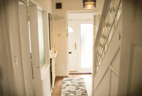 a hallway with a staircase and a door with a rug at House in Colnbrook near Windsor & Heathrow in Colnbrook