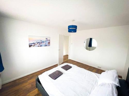 a bedroom with a white bed and a painting on the wall at House in Colnbrook near Windsor & Heathrow in Colnbrook