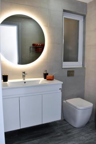 a bathroom with a sink and a mirror and a toilet at Golden Rays Apartment in Nadur