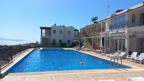 a person swimming in a swimming pool next to a building at İBAK Apartments in Gümüşlük