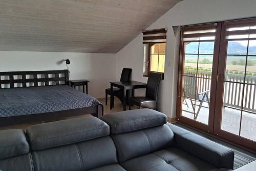 ein Schlafzimmer mit einem Bett und einem Sofa sowie einem Balkon in der Unterkunft Apartman FARMA HRADEC in Mnichovo Hradiště