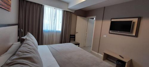 a hotel room with a bed and a flat screen tv at Fuente Mayor Hotel Centro in Mendoza