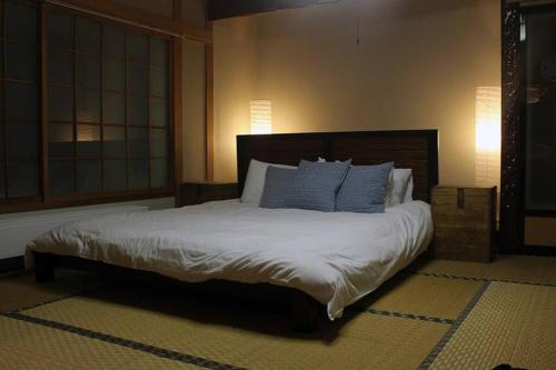 1 dormitorio con 1 cama grande con almohadas azules en Rusutu Ski Chalet - Six Bedrooms, BBQ, Lake Toya., en Rusutsu