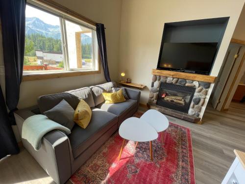 a living room with a couch and a tv and a fireplace at Riverside Condos by Fernie Central Reservations in Fernie