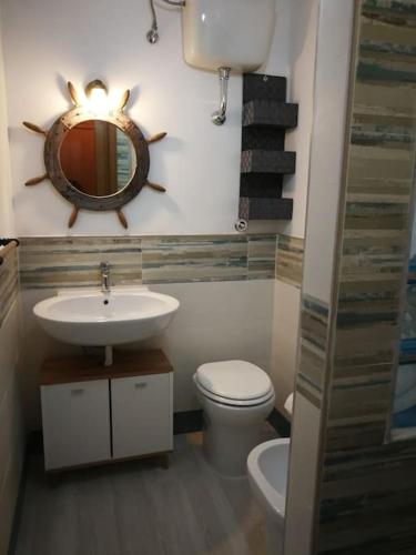 a bathroom with a sink and a toilet and a mirror at CAMBUSA. in Acciaroli