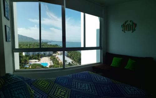 a bedroom with a bed and a large window with a view at Costa Azul Suites 1002 in Santa Marta