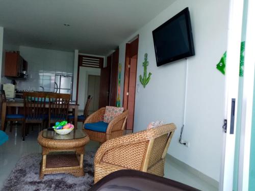 a living room with wicker chairs and a television at Costa Azul Suites 1002 in Papare