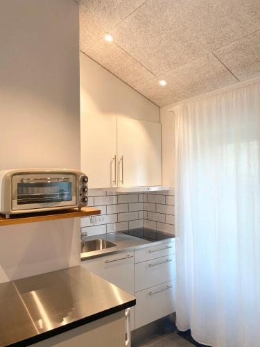 ナクスコウにあるTiny Guesthouseの白いキャビネットと電子レンジを備えたキッチン