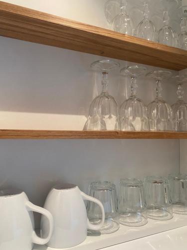 une rangée de verres et de tasses sur une étagère dans l'établissement Tiny Guesthouse, à Nakskov
