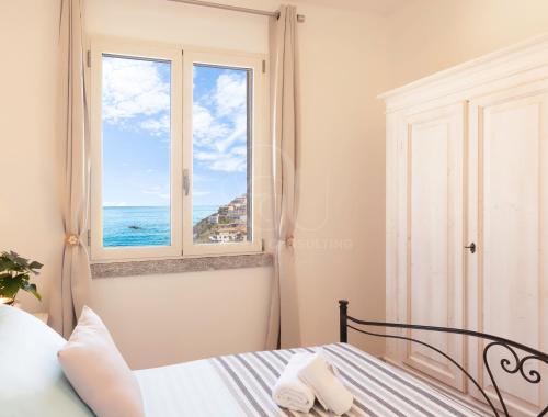 a bedroom with a bed and a window with the ocean at IL Castello incantato in Castelsardo