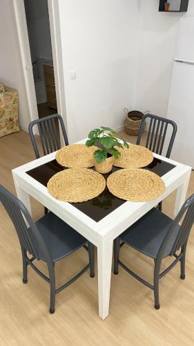 a white table with four plates and a plant on it at Apartamento Retama Laguna Centro in Las Lagunas
