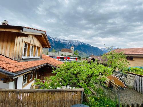 a train is traveling past a house with a mountain at Royal Swiss Apartments in Ringgenberg