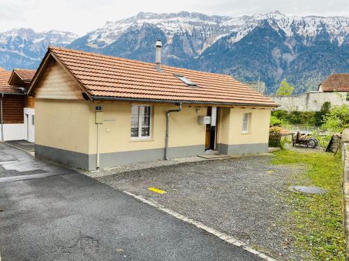 a small yellow building with mountains in the background at Royal Swiss Apartments in Ringgenberg