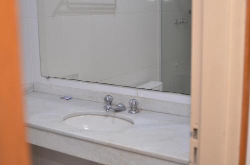 um balcão de casa de banho com um lavatório e um espelho em Tuti Bororô em Rondonópolis