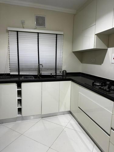 een keuken met witte kasten en zwarte aanrechtbladen bij Modern City Center 3-Bed Apartment in Abuja