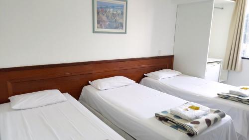 2 Betten in einem Zimmer mit weißer Bettwäsche in der Unterkunft Pousada Suites in Brasilia