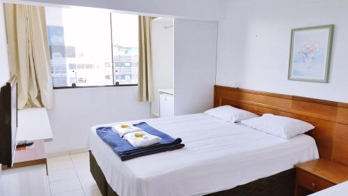 Schlafzimmer mit einem Bett mit weißer Bettwäsche und einem Fenster in der Unterkunft Pousada Suites in Brasilia