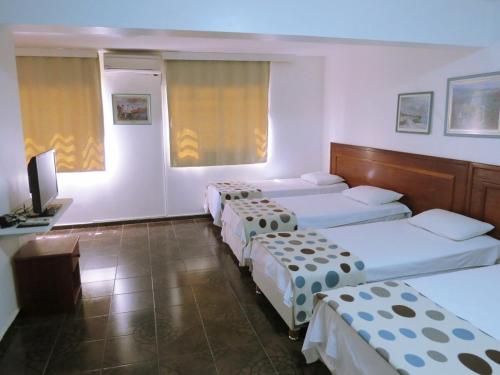 eine Gruppe von 3 Betten in einem Zimmer mit einem TV in der Unterkunft Pousada Suites in Brasilia