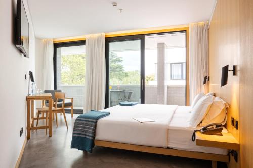 a bedroom with a bed and a large window at Evora Olive Hotel in Évora