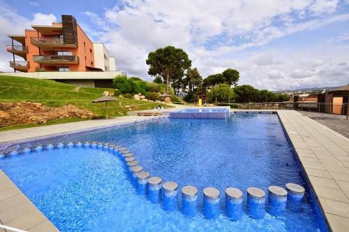 une grande piscine d'eau bleue en face d'un bâtiment dans l'établissement Pretty garden apartment next to a charming beach, à Lloret de Mar