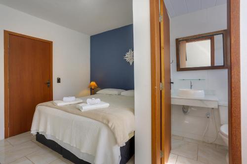 a bedroom with a bed and a bathroom with a sink at Apart Carolina in Florianópolis