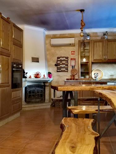 a kitchen with wooden cabinets and a table with a fireplace at Casinha Siberiana, Casa de Hospedes in Vila da Ponte