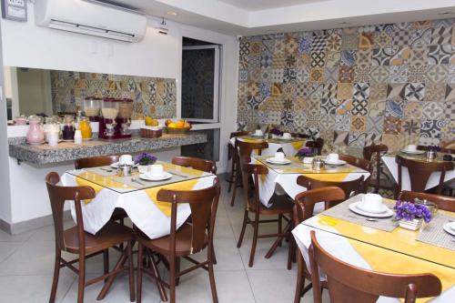 una sala da pranzo con tavoli e sedie in un ristorante di Minuano Hotel Express próx Orla Lago Guaíba, Mercado Público, 300 m Rodoviária a Porto Alegre