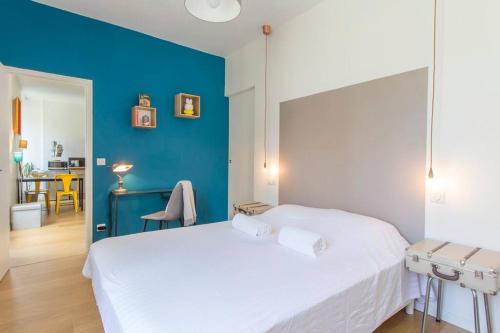 - une chambre avec un lit blanc et un mur bleu dans l'établissement Le Jaurès, logement d’exception, à Grenoble