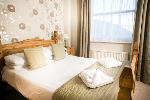 a bedroom with a bed with white sheets and a window at The Cumberland Hotel in Eastbourne