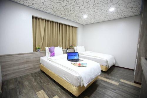 a hotel room with two beds with a laptop on it at 心園生活旅店 Xin Yuan Hotel in Hsinchu City