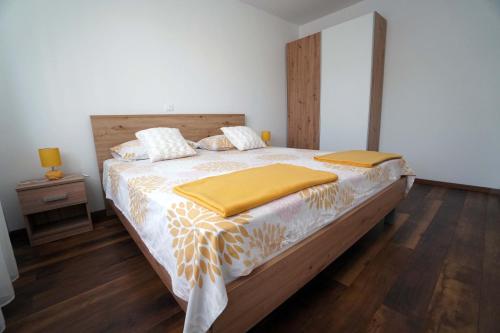 a bedroom with a large bed with a wooden headboard at Apartman Petra in Brodarica