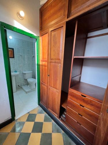 a bathroom with a toilet and a wooden cabinet at Green Door San Gil in San Gil