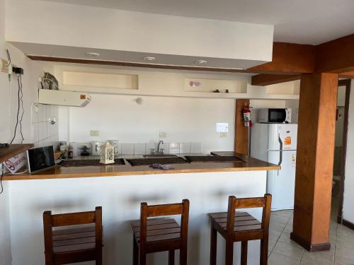 a kitchen with a counter and three bar chairs at Mirando al canal in Ushuaia