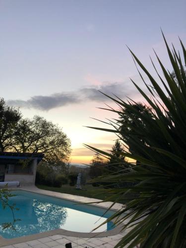 a swimming pool with a sunset in the background at Une pause quelque part ... in Vic-Fezensac