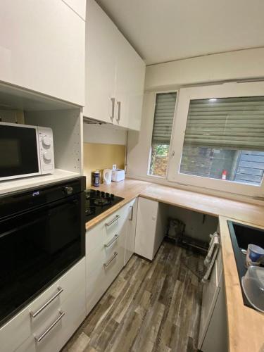 uma cozinha com armários brancos, um lavatório e um micro-ondas em La singulière em Cergy